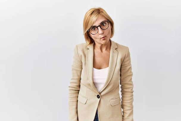 Middle age blonde business woman standing over isolated background making fish face with lips, crazy and comical gesture. funny expression.  - Φωτογραφία, εικόνα