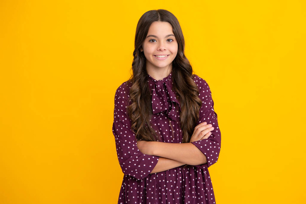 Portrait of young teenage girl standing with crossed arms against yellow background with copy space - Foto, Imagem