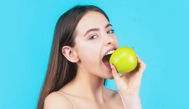 Healthy diet food. Stomatology concept. Woman with perfect smile holding apple, blue background. - Fotó, kép