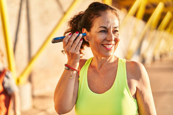 Middle age hispanic woman working out listening voice message at promenade - Foto, Imagen