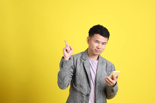Азиатский ЛГБТК-человек в сером пиджаке стоит на желтом фоне. - Фото, изображение