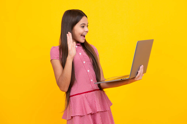 Amazed teen girl. Teenager school girl hold notebook laptop. School children on isolated studio background. Excited expression, cheerful and glad - Foto, Imagem