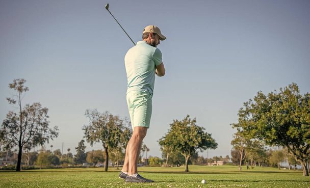 Profesyonel golf sahasında erkek golfçü. Golf sopasıyla şapkalı golfçünün portresi. İnsanların yaşam tarzı. Aktif bir adam yeşil çimlerde oyun oynuyor. Yaz etkinliği. Profesyonel spor.. - Fotoğraf, Görsel