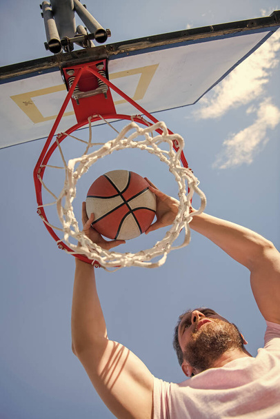 dunk in basket. slam dunk in motion. summer activity. energetic man with basketball ball on court. professional basketball player training outdoor. guy has sport motivation. sport and hobby. - Foto, afbeelding