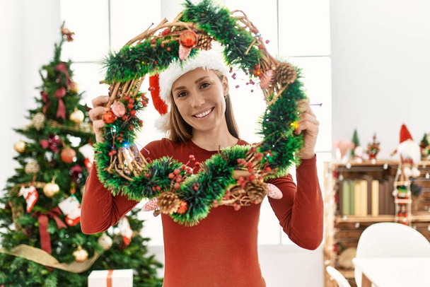 Jeune femme caucasienne souriante confiante tenant décor de Noël à la maison - Photo, image