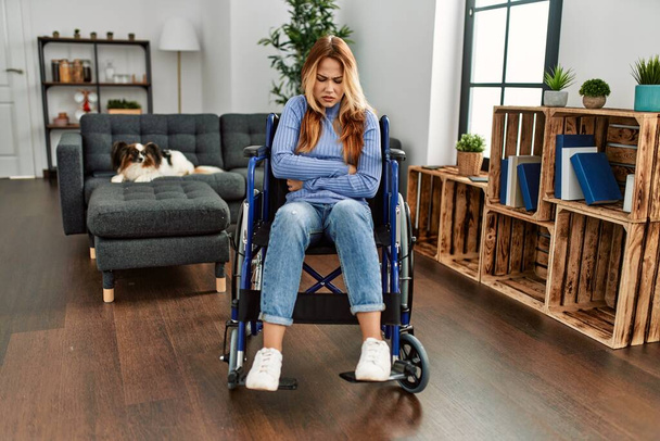 Young beautiful woman sitting on wheelchair at home with hand on stomach because nausea, painful disease feeling unwell. ache concept.  - Photo, Image