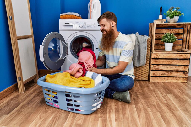 Young redhead man smiling confident washing clothes at laundry room - Fotoğraf, Görsel