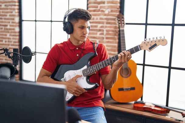Mladý hispánec muž hudebník hraje na elektrickou kytaru v hudebním studiu - Fotografie, Obrázek