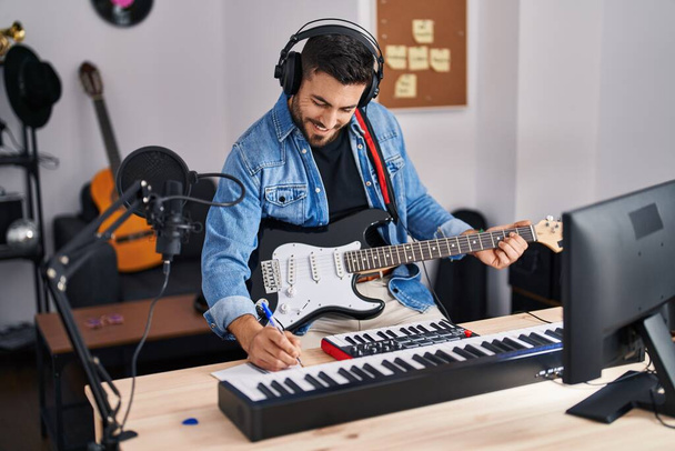Genç İspanyol adam müzik stüdyosunda elektro gitar çalarak şarkı söylüyor. - Fotoğraf, Görsel