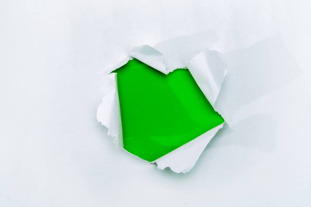 A hole in white paper with torn edges and a green isolated background inside, Ripped grenn and white paper, copy space - Foto, afbeelding