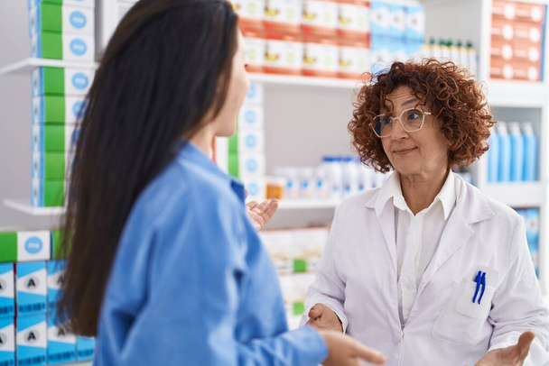 Two women pharmacist and customer speaking at pharmacy - Zdjęcie, obraz