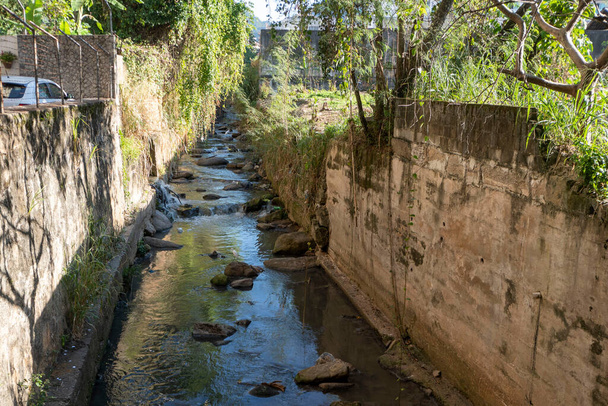 widok na rzekę Maracana, która jest zdegradowana i zanieczyszczona drzewami wokół niej w dzielnicy Tijuca - Zdjęcie, obraz