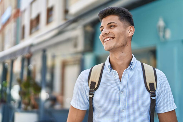 Young hispanic man student smiling confident standing at street - 写真・画像