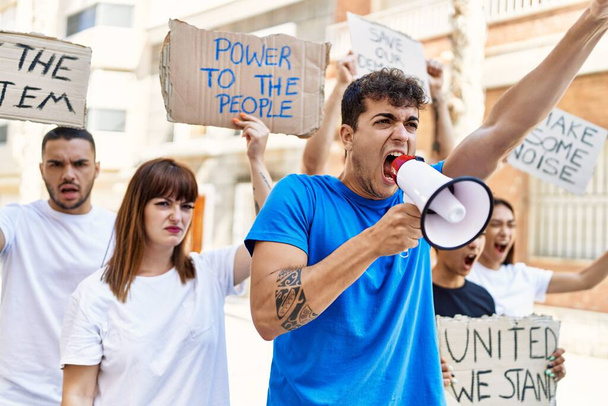 Grupo de jóvenes activistas que protestan con pancartas y usan megáfono en la ciudad. - Foto, imagen