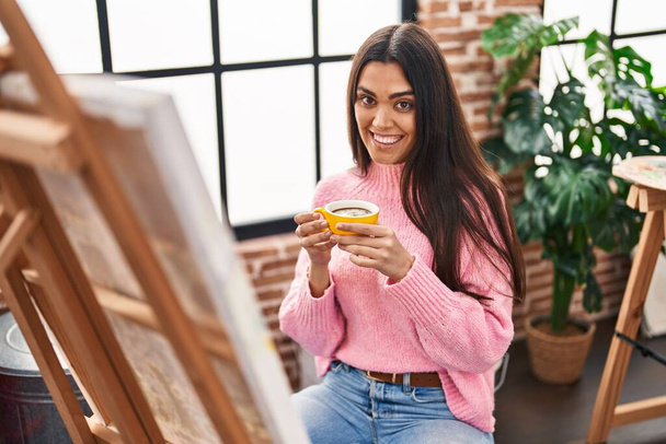 Genç İspanyol kadın resim stüdyosunda kahve içiyor. - Fotoğraf, Görsel