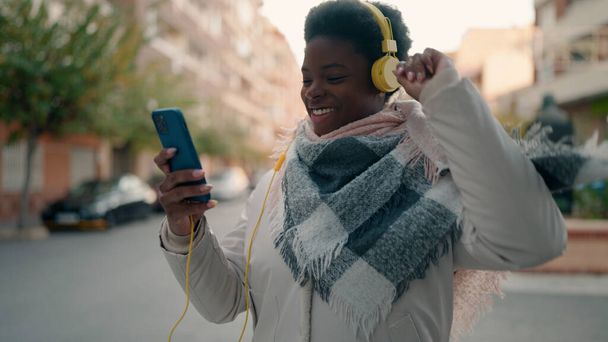 Young african american woman listening to music using smartphone at street - Foto, Imagen