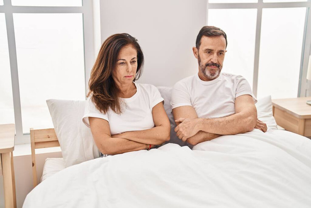 Чоловік середнього віку і жінка пара нещасливі сидячи в ліжку в спальні
 - Фото, зображення