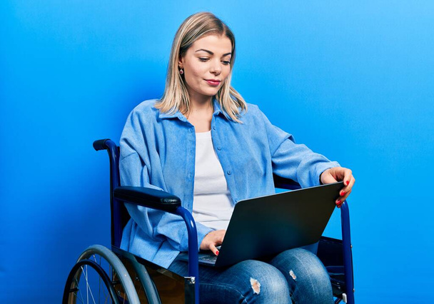 Красивая белая женщина сидит на инвалидной коляске с помощью ноутбука мышление отношение и трезвое выражение лица выглядит уверенным в себе  - Фото, изображение