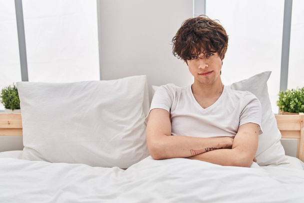 Young hispanic man unhappy sitting on bed at bedroom - Photo, Image