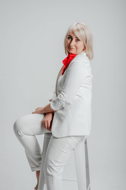 a woman in a white suit with a red scarf on a white background - 写真・画像