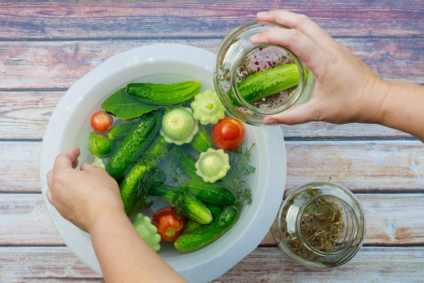 Pickling cucumbers, tomatoes, and squash in glass jars. - Photo, Image