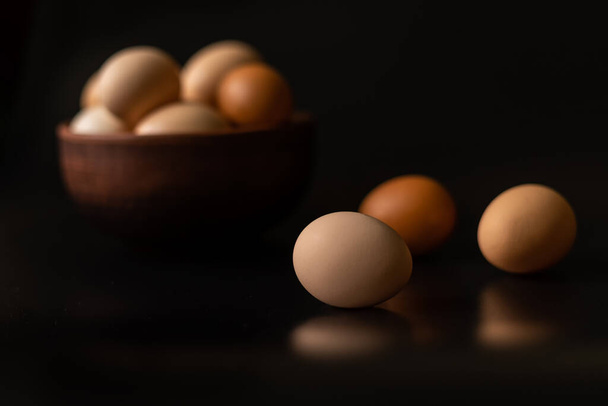 Eggs of different shades in a bowl  on a black background - Foto, afbeelding