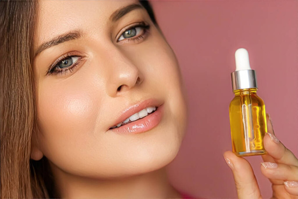 Beauty, makeup and skincare cosmetics model face portrait, woman holding skin care cosmetic essential oil bottle with dropper, luxury facial care product mockup - Foto, afbeelding