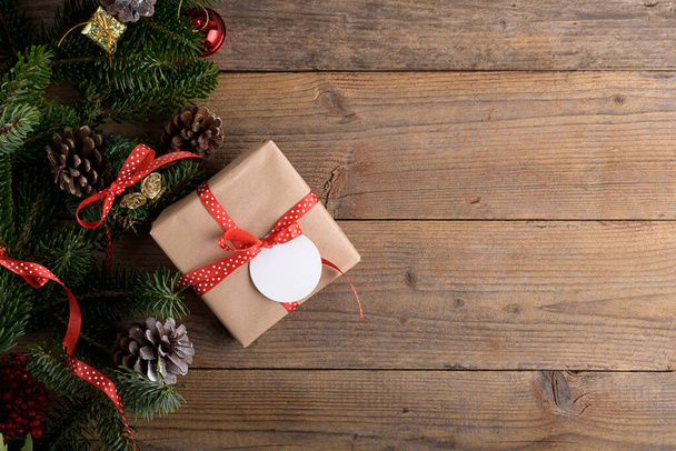 Kerst spar boom decoratie frame met geschenk op rustieke houten achtergrond. Kerst achtergrond met sparren takken, rode bessen, kegels, platte lay en kopieer ruimte, element voor ontwerp - Foto, afbeelding