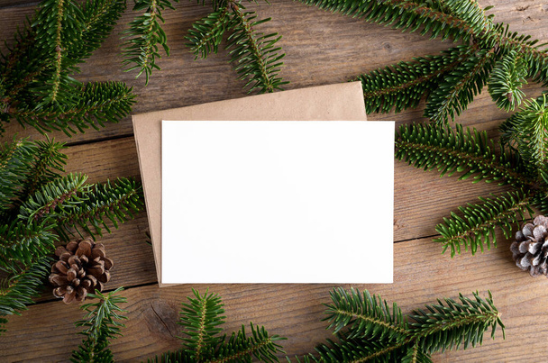 Karácsonyi 7x5 kártya mockup sablon boríték fenyő gallyak és karácsonyi dekoráció fa háttér. Tervezési elem a karácsonyi és újévi gratuláció, üdvözlő vagy meghívó kártya - Fotó, kép