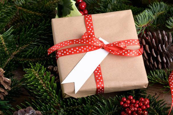 Різдвяна прямокутна стрічка подарункова мітка макет з подарунковою коробкою, макет етикетки продукту, з натуральною гілкою ялинки, конусами та різдвяними прикрасами, концепція різдвяних продажів. Порожня паперова прямокутна мітка назви
 - Фото, зображення