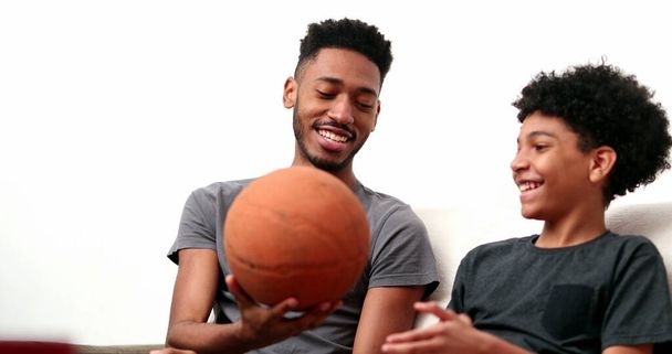 Brothers bonding together with basketball. Mixed race, black ethnicity siblings playing and spinning ball - Photo, image