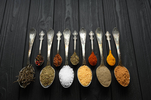 Colorful various herbs and spices for cooking on dark wooden rustic background - 写真・画像