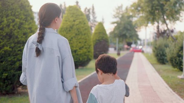 Mother and son walking holding hands along the alley. High quality 4k footage - Fotoğraf, Görsel