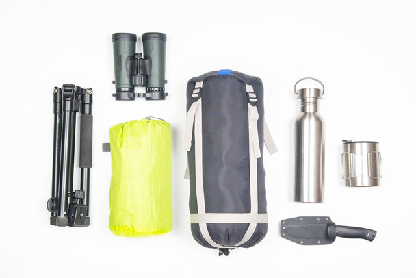 necessary items for tourism and travel. sleeping bag, rug, binoculars, knife, mug, thermos on a white background - Valokuva, kuva