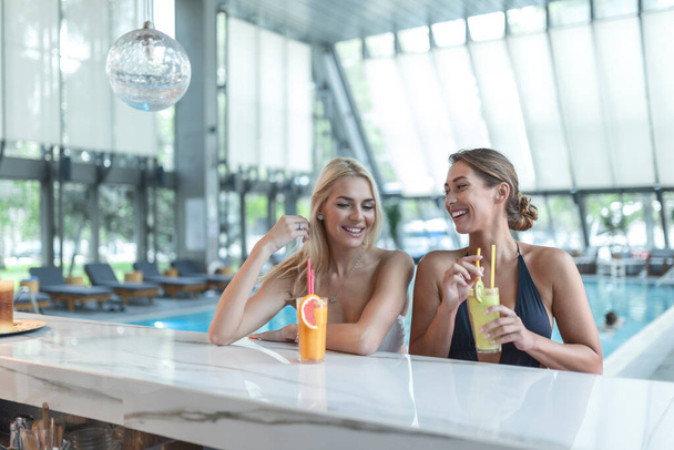 Women friends drink, cocktail mojito on pool bar, wear bikini luxury hotel near beach on tropical island relax - Foto, Imagen