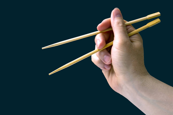 bamboo chopsticks in a male hand on a dark background. items for food - Фото, зображення