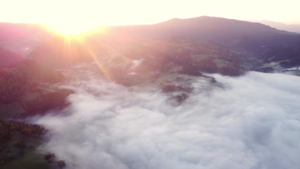 Воздушный беспилотный вид тумана и перевернутых облаков в сельской долине в горном ландшафте Карпат, на восходе солнца. Яркое солнце, восходящее из-за гильз. - Кадры, видео