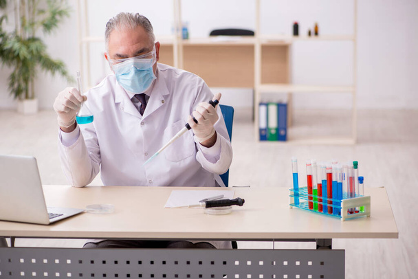Stary chemik pracujący w laboratorium podczas pandemii - Zdjęcie, obraz