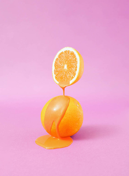 Minimal surreal composition with halved orange fruit and liquid against pastel purple background. Creative vegan diet idea. - Фото, изображение