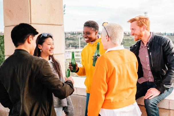 Giovani amici multietnici che si incontrano bevendo birra e divertendosi. foto di alta qualità - Foto, immagini