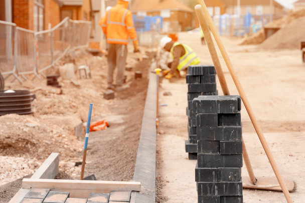 Builders installing paving blocks during road and footpath construction on a semi-dray concrete mix. Block paving footpath in progress - Photo, Image