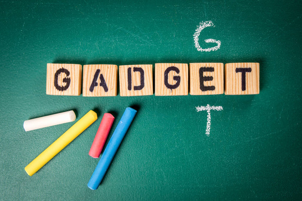 Get Gadget concept. Wooden alphabet letters and pieces of chalk on a green chalk board. - Foto, Bild