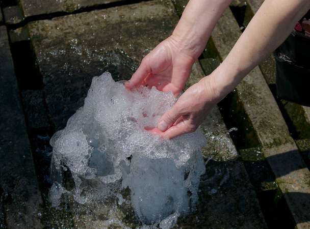 As mãos tocam na fonte. Uma corrente de água da fonte é tocada pelas mãos. Conceito de frescura e frescura
 - Foto, Imagem