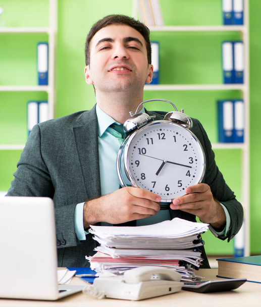 Бизнесмен зол из-за чрезмерной работы, сидя в офисе в концепции управления временем
 - Фото, изображение