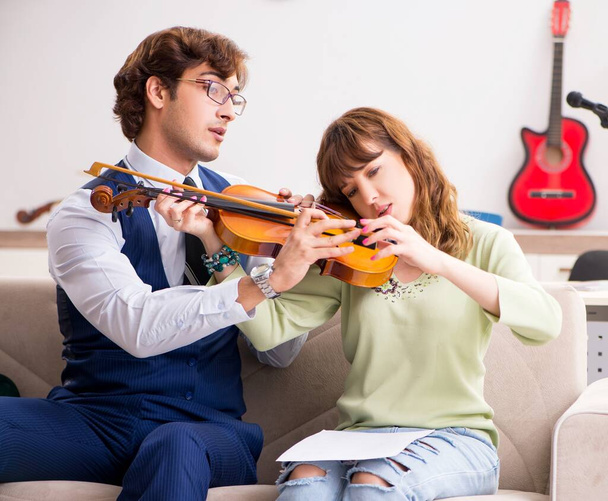 La mujer joven durante la lección de música con el profesor masculino
 - Foto, Imagen