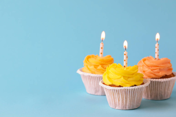 Tasty birthday cupcakes with candles on light blue background. Space for text - Foto, Imagen