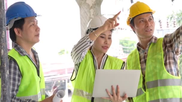 Grupo de ingeniera asiática o arquitecta joven se puso un casco para la seguridad y hablar con un contratista en un proyecto de fábrica de construcción, concepto de trabajo en equipo, concepto de liderazgo. - Metraje, vídeo