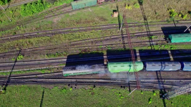 Αεροφωτογραφία από ιπτάμενο drone πολύχρωμων εμπορευματικών αμαξοστοιχιών στο σιδηροδρομικό σταθμό - Πλάνα, βίντεο