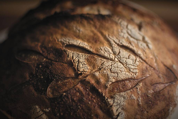 Perfect sourdough bread over a wooden table right out of the oven. - Fotoğraf, Görsel