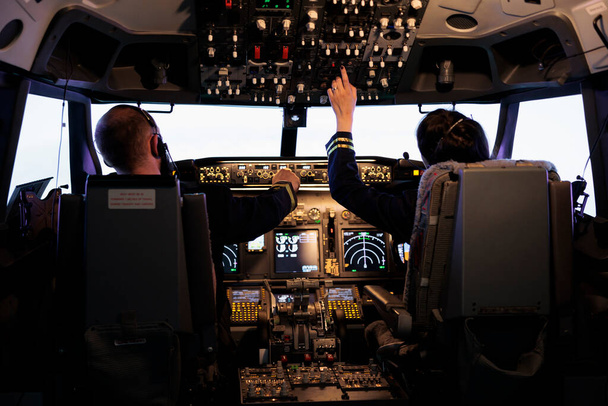 Capitão e mulher co-piloto se preparando para voar avião e decolagem com navegação painel no comando cockpit. Tripulação de linha aérea fixando nível de altitude e com botões do painel de controle, avião voador. - Foto, Imagem